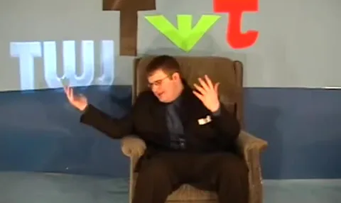 Jon throwing his arms up in the armchair on the TWJ set